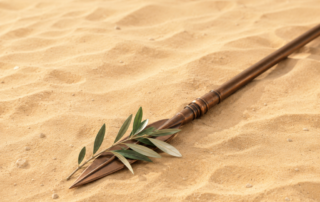 Un paysage désertique serein, baigné de tons dorés chaleureux, présente de douces ondulations de sable et quelques petits cailloux épars. Au premier plan, une lance en bronze à la pointe angulaire et légèrement patinée repose en diagonale dans la scène, accompagnée d’un petit rameau d’olivier, créant une nature morte paisible et minimaliste sur un sable tranquille.